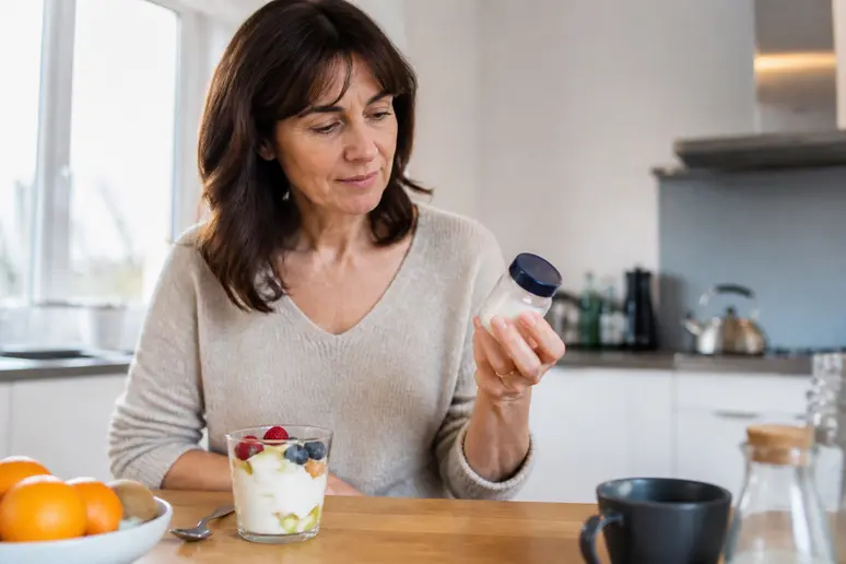 Une femme s'interroge sur un bonbon sans sucre danger, remplaçant le sucre dans son petit-déjeuner sain.