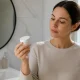 Un flacon de cosmétique tenu en main pour illustrer comment alpha arbutin éclaircir peau en toute sécurité.