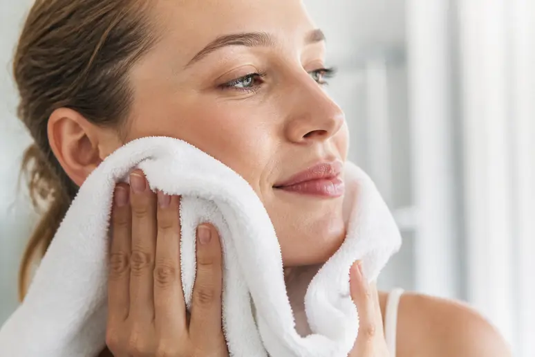 Séchage délicat du visage avec une serviette propre avant d'appliquer un soin cutané.