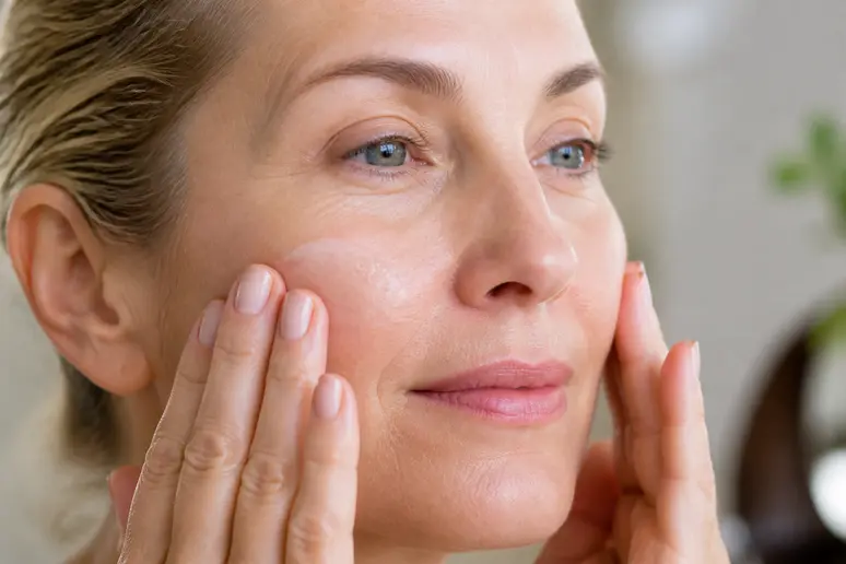 Mains appliquant une crème anti-âge par pressions douces pour éviter l'effet de peluchage