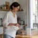 Personne préparant un verre d'eau dans une cuisine lumineuse pour illustrer un Kijimea avis syndrome intestin irritable