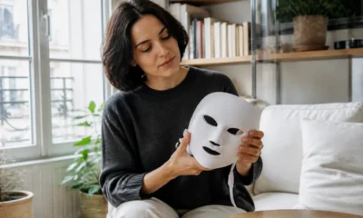 Une femme tient délicatement un masque Current Body rides dans son salon lumineux à Paris.