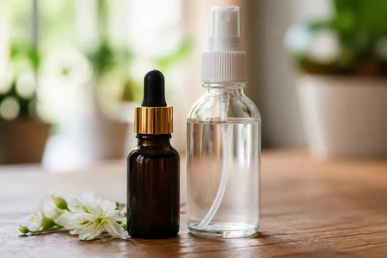 Flacon spray d hydrolat et fiole d huile essentielle posés sur une table en bois