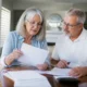Un couple de seniors examine des documents administratifs pour choisir une mutuelle après 60 ans à domicile.